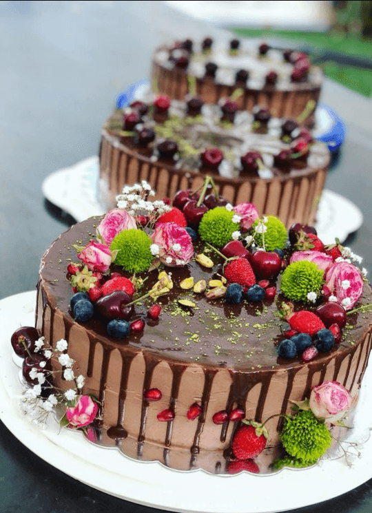 Chiflika's signature three-tier chocolate drip cake with berries and flowers